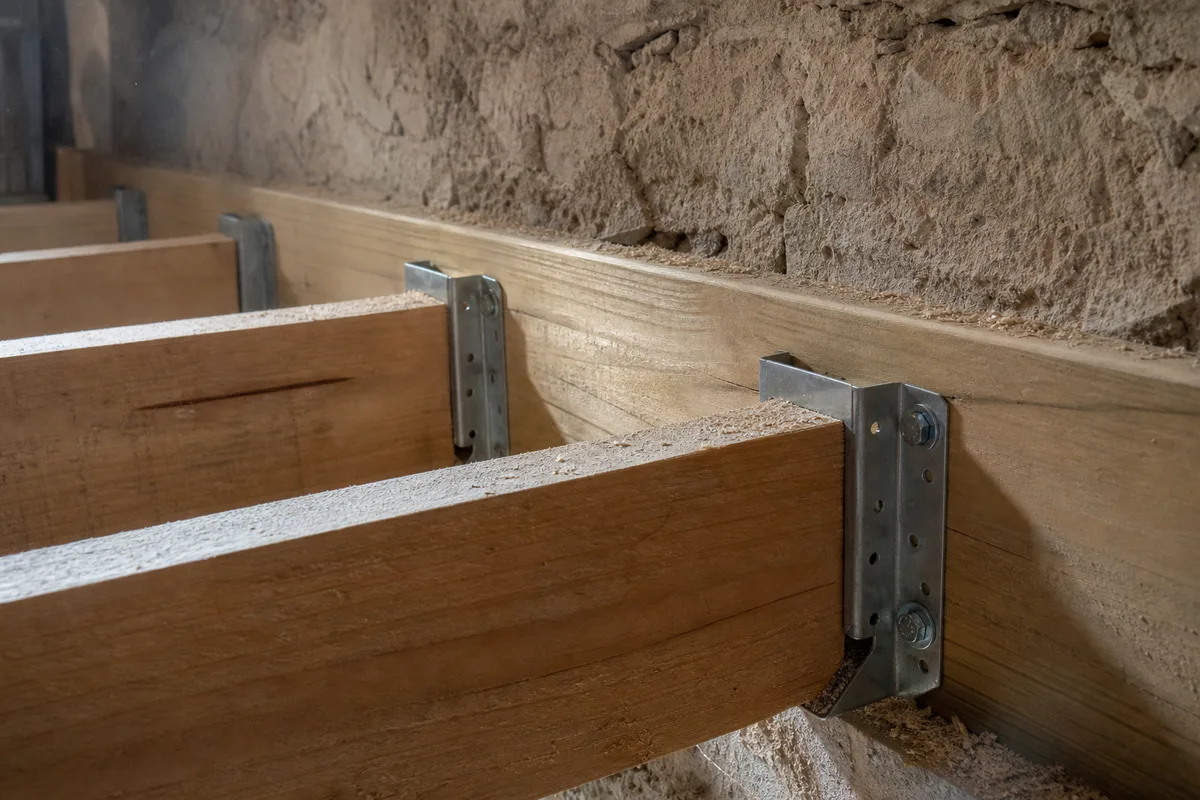 Mezzanine bois en cours d’aménagement sous une charpente ancienne, solives apparentes